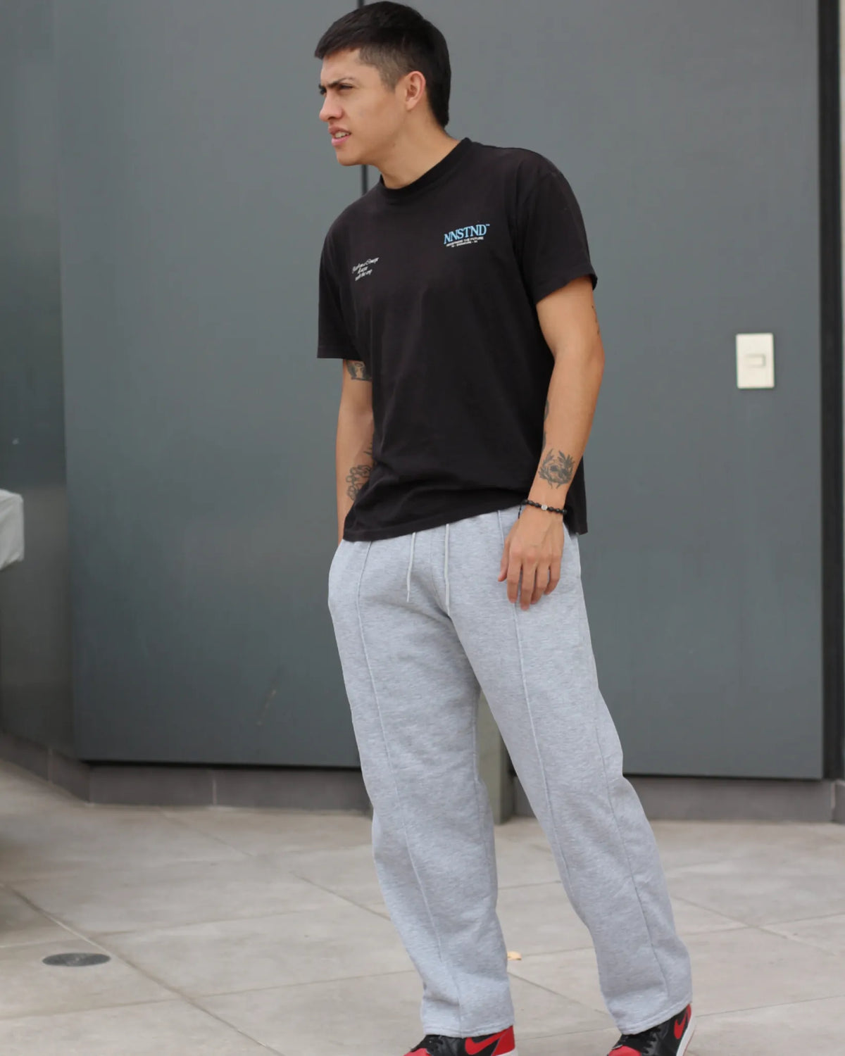 Man wearing a black t-shirt and grey sweatpants from TU SHOP.