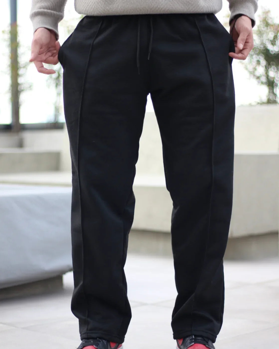 Person wearing TU SHOP black urban sweatpants with drawstring waist.