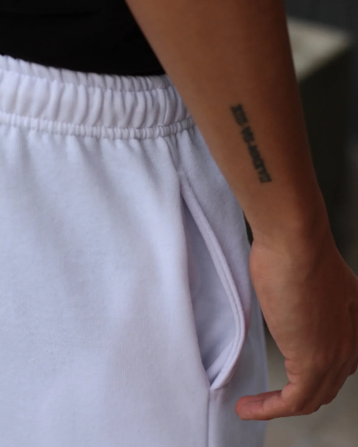 Close-up of a person wearing white TU SHOP urban sweatpants with a pocket.